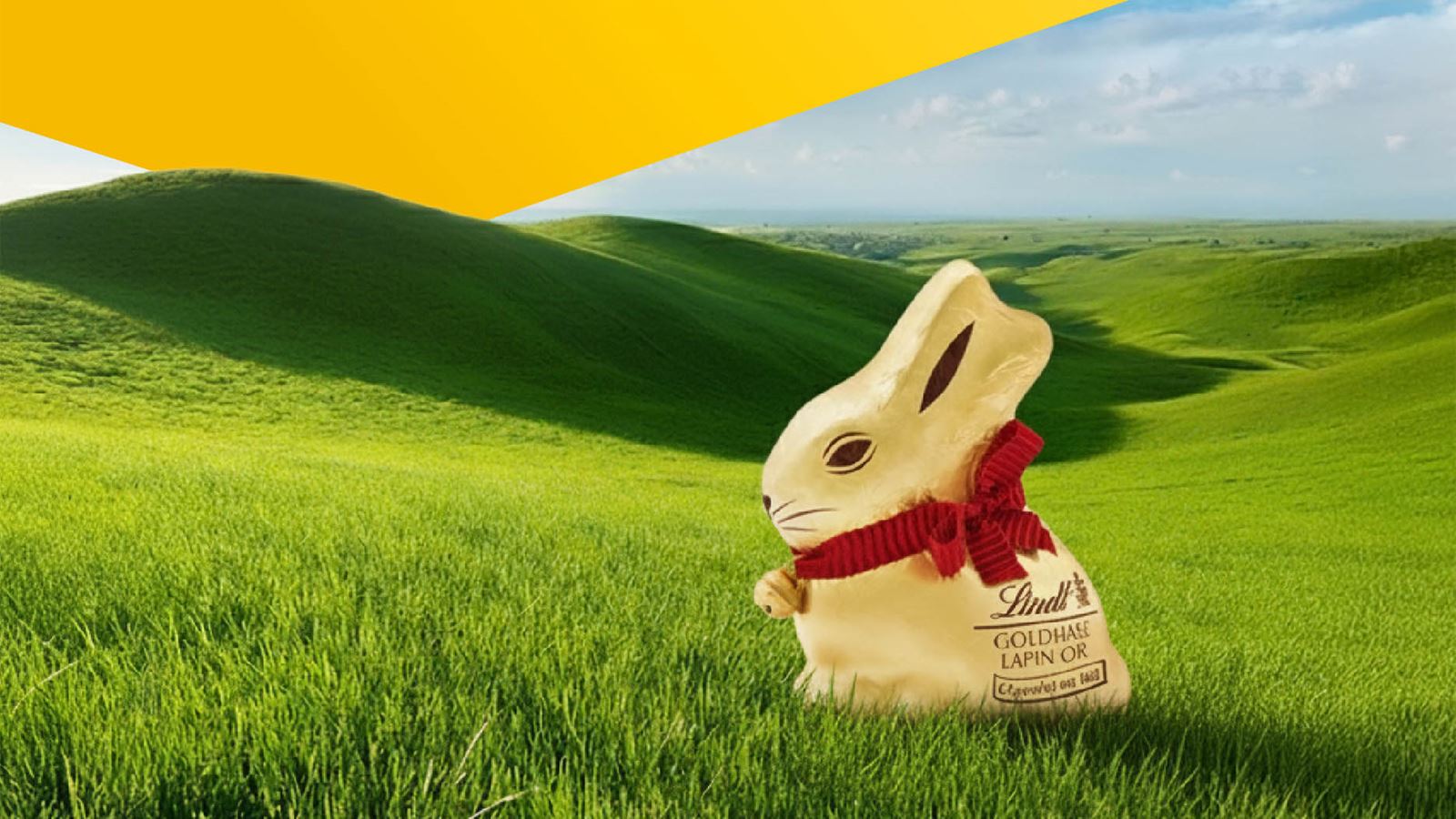 Lindt hare on a green meadow (yellow triangle above between sky and hill)