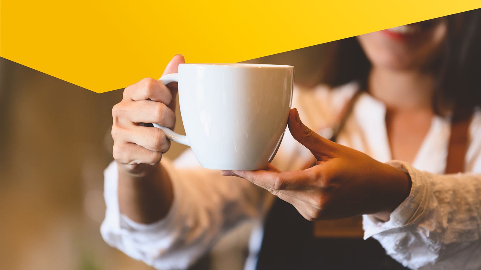 Eine Frau hält eine Tasse Kaffee in die Kamera (mit gelbem Designelement darüber)