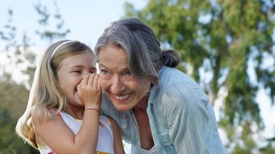 Ein Kind flüstert einer Frau etwas ins Ohr